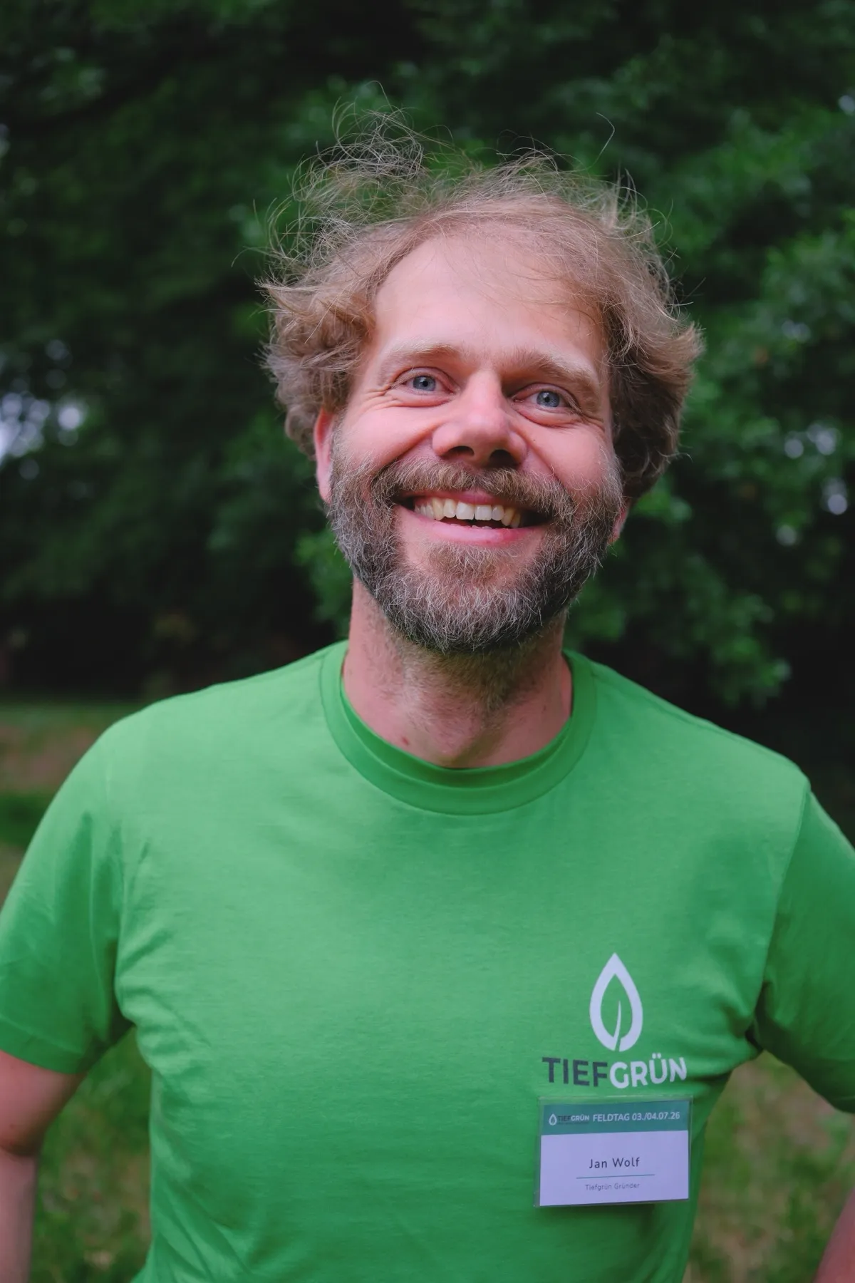 Jan Wolf lacht in die Kamera, im grünen TIEFGRÜN-Shirt